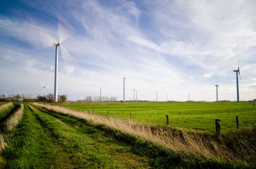 Free A scenic view of wind turbines in a green rural farm landscape under a bright sky. Stock Photo
