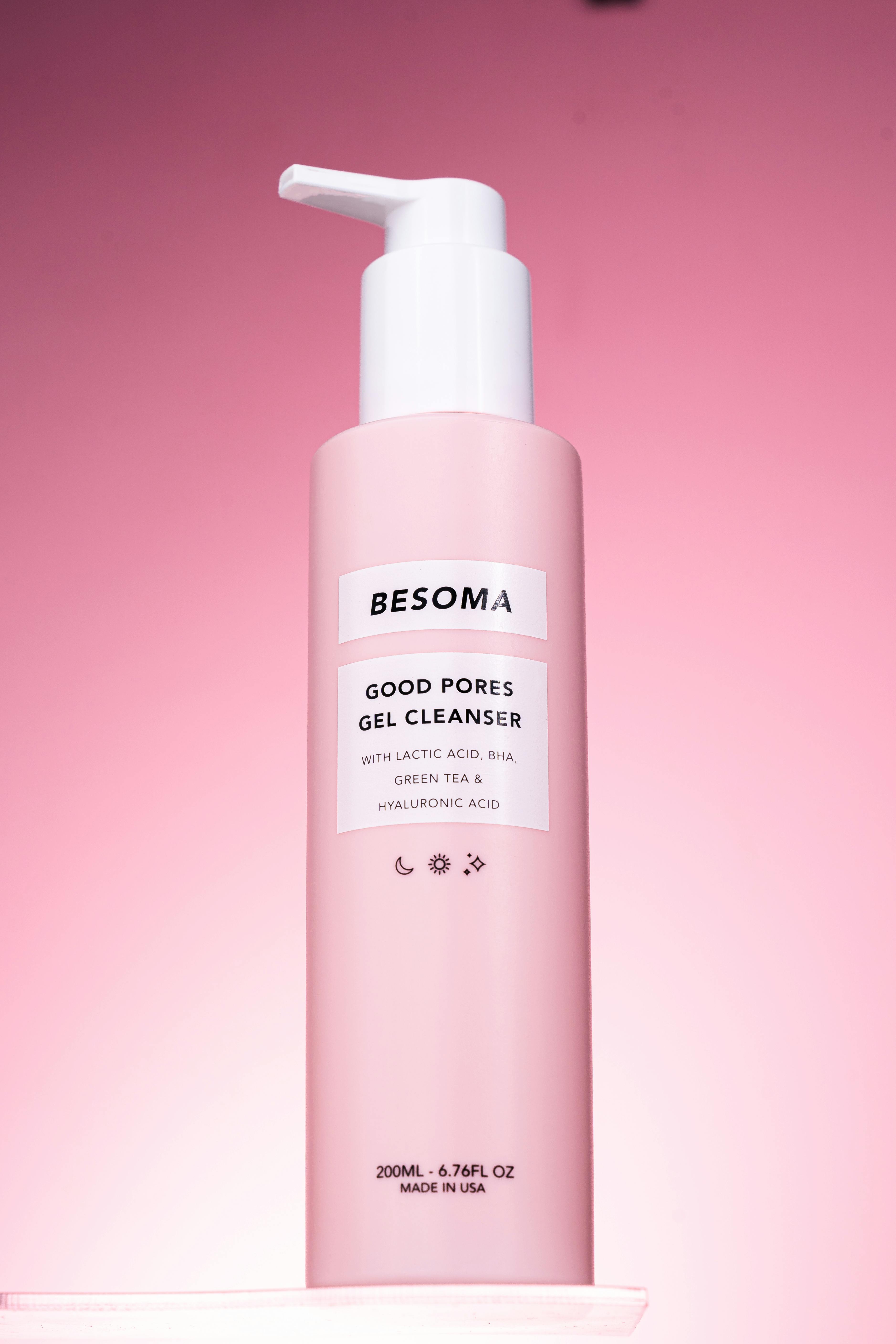 Stylish cosmetic gel cleanser bottle with pink hue, isolated on a vibrant background.