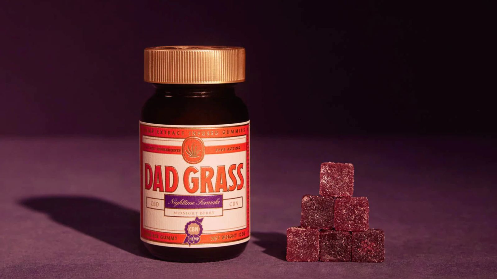 Close-up of Dad Grass nighttime CBD gummies in a jar with berry flavor.