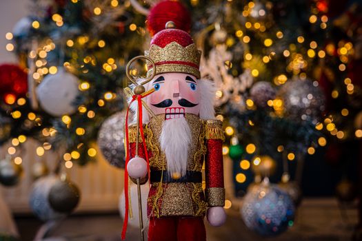 Close-up of a festive nutcracker figurine in front of a sparkling Christmas tree with bokeh lights.