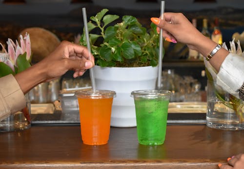 Women Hands Holding Straws of Fruit Cocktails