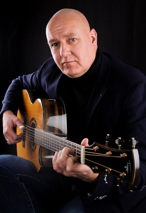 Free Close-up of a bald man playing an acoustic guitar in a studio setting. Stock Photo
