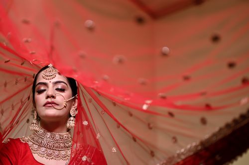 Free Beautiful Indian bride with eyes closed, adorned in traditional jewelry and red veil, showcasing elegance. Stock Photo