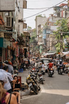 在阳光明媚的日子里，河内东达的街头生活充满活力，摩托车、商店和行人随处可见