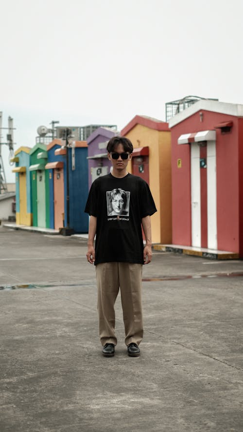 Man in T-shirt Standing near Colorful Sheds