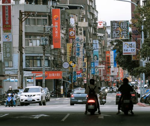 Free Urban scene in Taipei with vehicles, motorbikes, and vibrant street signage capturing city life. Stock Photo