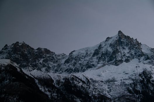 Snow-covered peaks of Chamonix-Mont-Blanc under an overcast sky, capturing the serenity of winter in the French Alps.