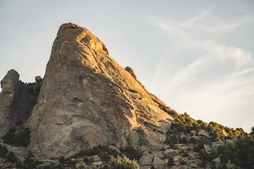 Free A stunning view of a rocky mountain peak bathed in warm sunlight under a clear sky. Stock Photo