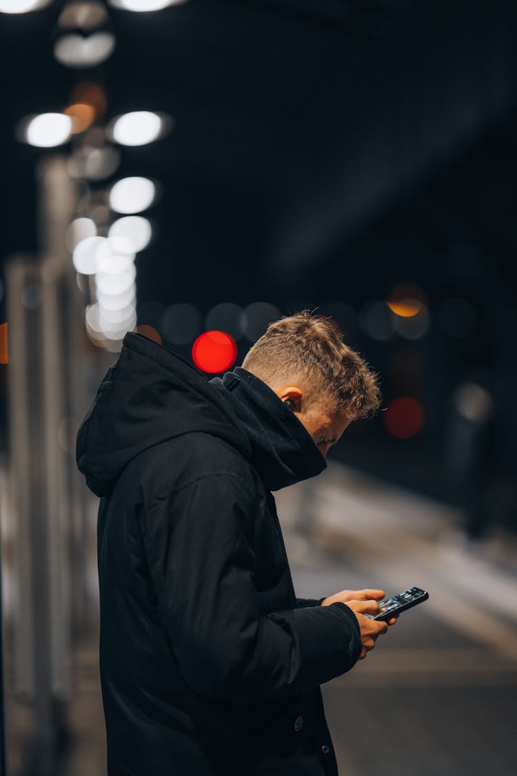 Man In Outerwear Using Phone On Street