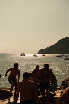 People enjoying a seaside view at sunset with boats on the horizon.