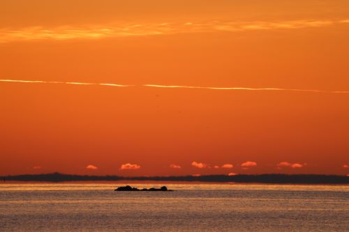 Free Beautiful ocean view at golden hour with a vivid orange sky and serene seascape. Stock Photo