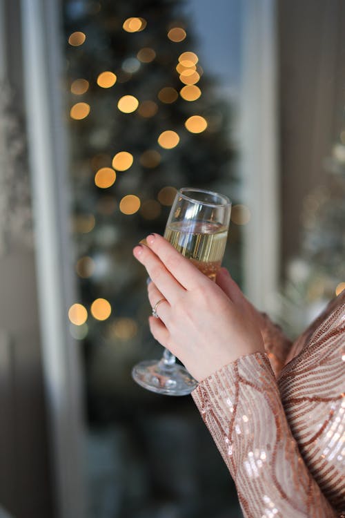 Woman with Glass Celebrating near Christmas Tree