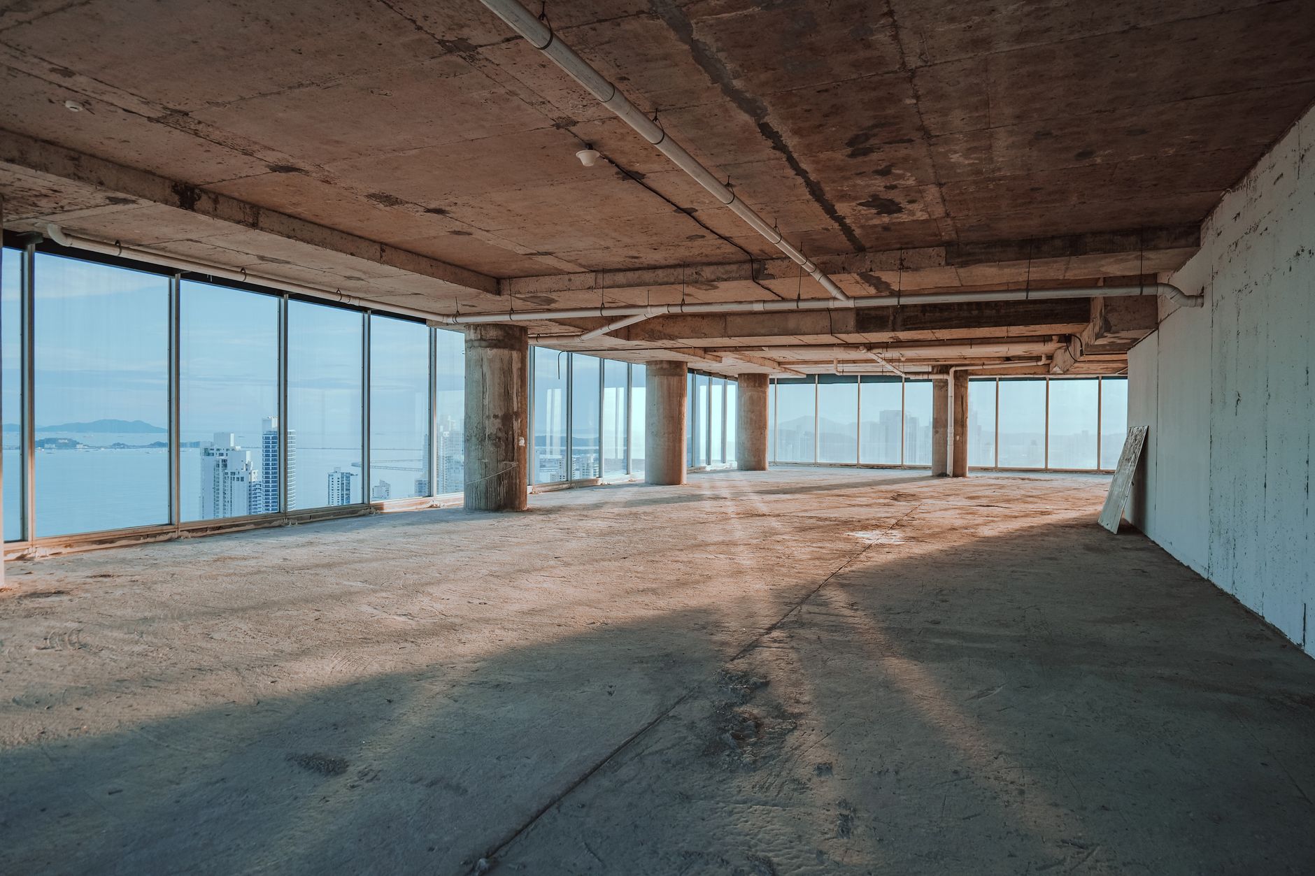Spacious empty interior with large windows overlooking city skyline.