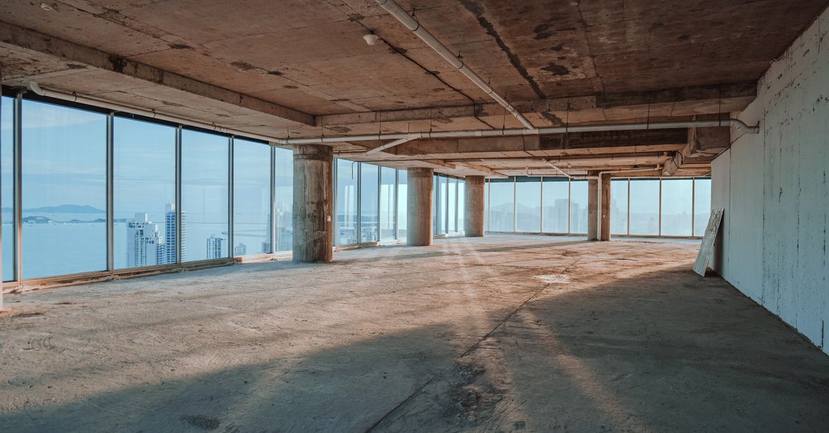 Spacious empty interior with large windows overlooking city skyline.