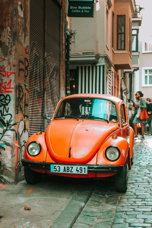 Free Classic red Volkswagen Beetle parked in a narrow graffiti-covered alley. Stock Photo