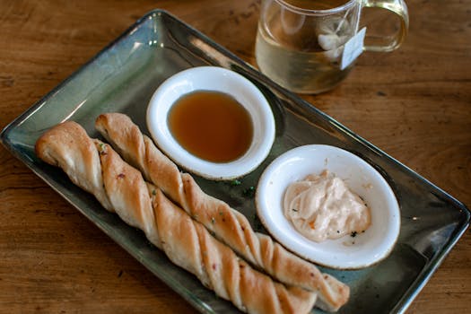 Appetizing breadsticks served with dips and herbal tea on a wooden table.