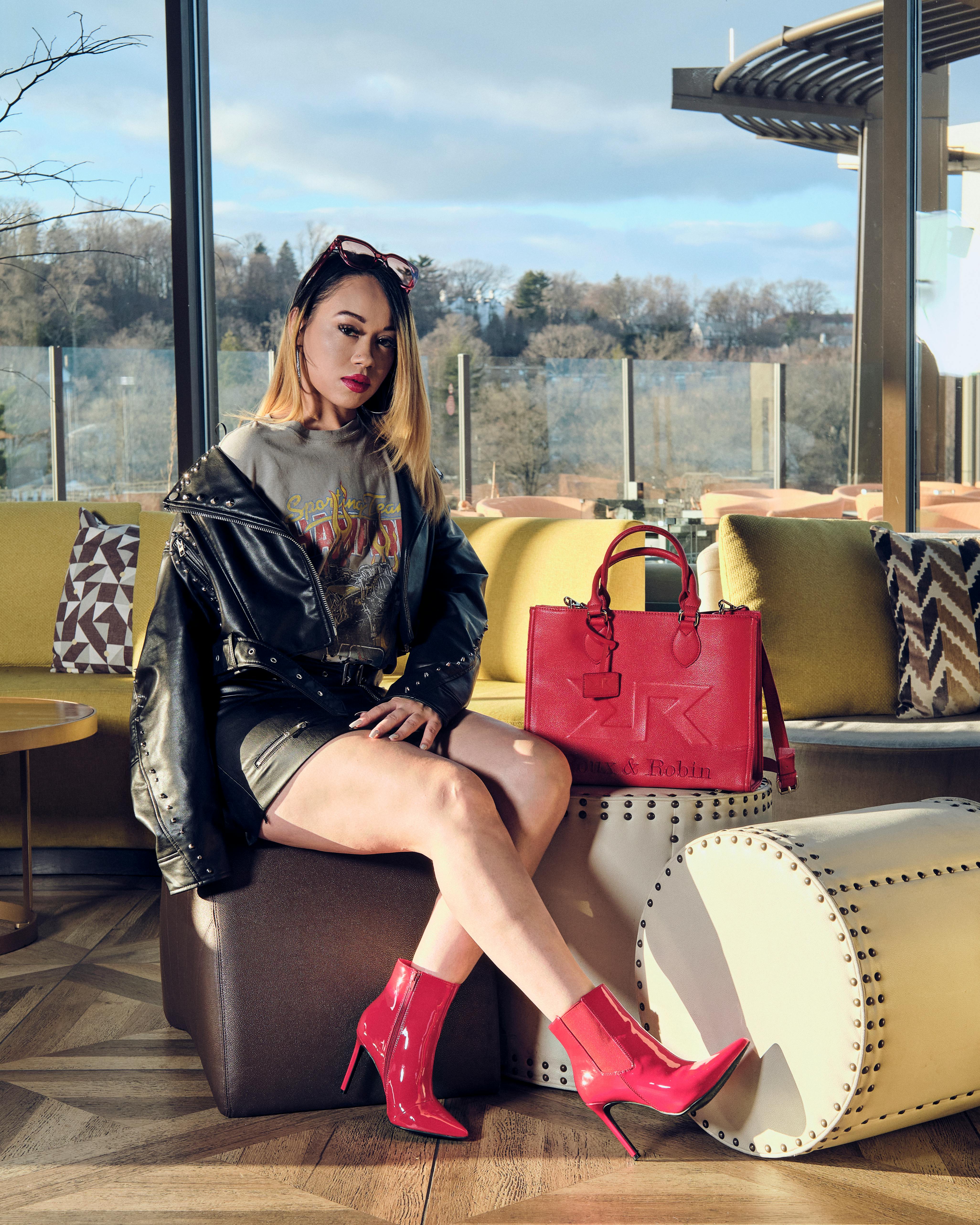 Free Fashionable woman in vibrant attire poses stylishly in an urban lounge with a scenic view. Stock Photo