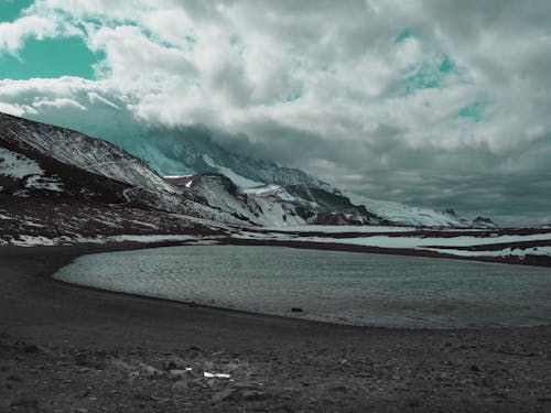 Body of Water in Front of Snow Covered Mountains