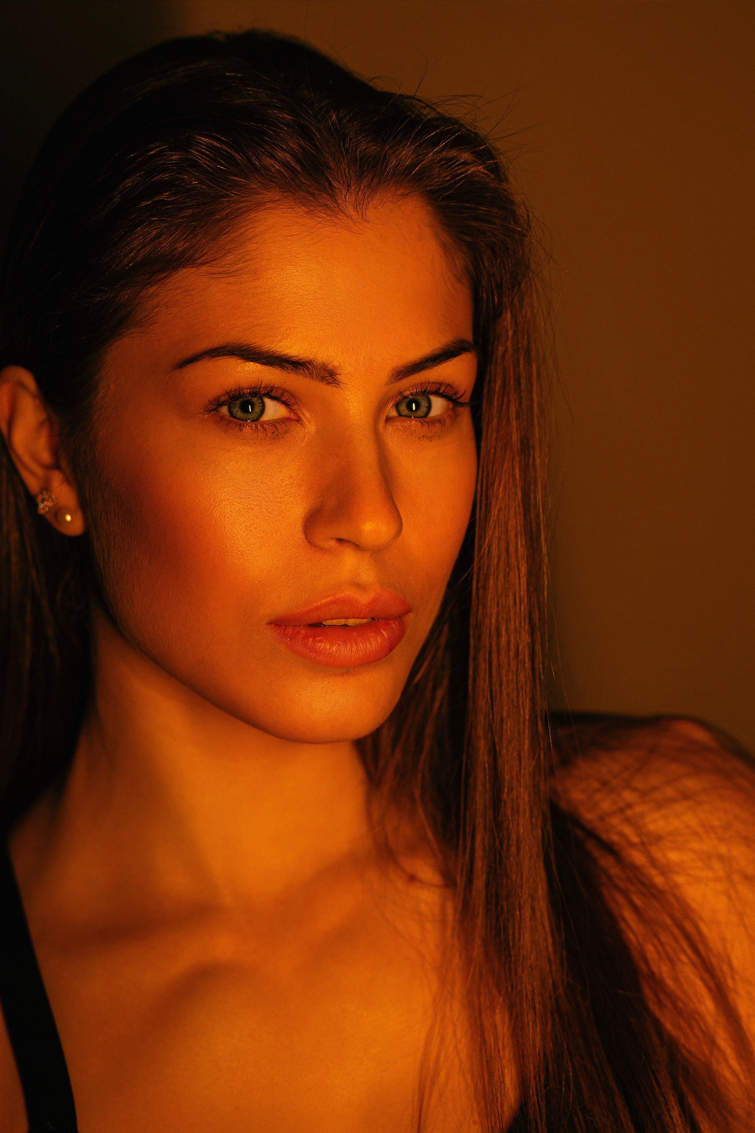 Close-up portrait of a woman illuminated by warm light, showcasing beauty and elegance.