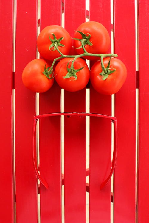 A Spring of Tomatoes and Red Sunglasses on a Red Table 