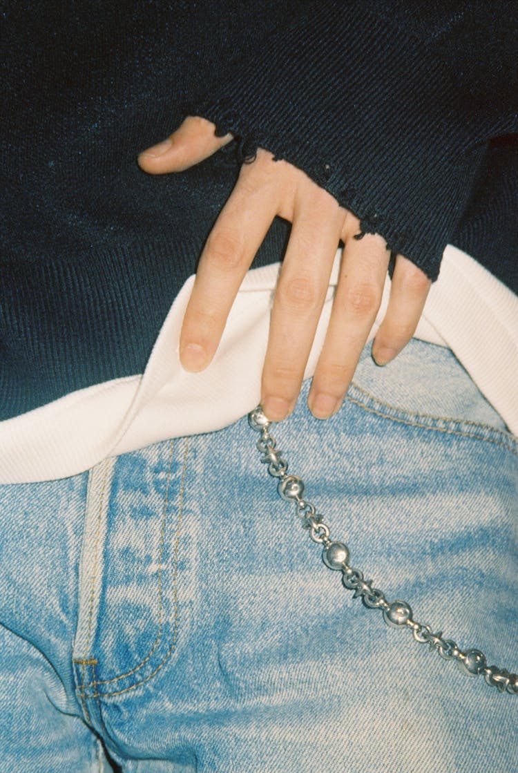 Photo Of A Hand, Jeans, A Chains, A White Shirt And A Black Sweater