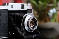 Close-up of a vintage bellows camera showing intricate lens details and retro design.