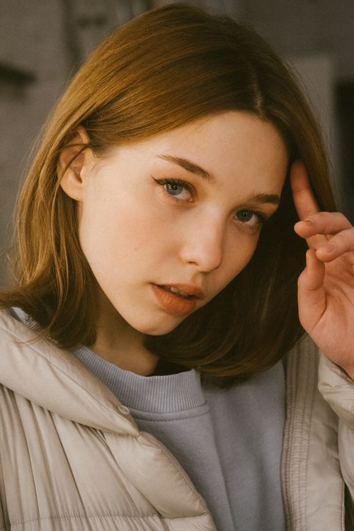 Free Close-up portrait of a young woman indoors with an expressive gaze and soft natural lighting. Stock Photo