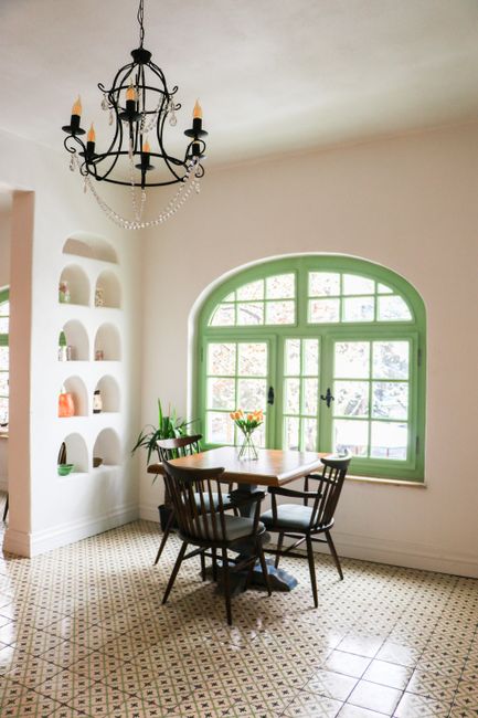 Inviting dining room featuring classic furniture, arched window, and elegant chandelier lighting.