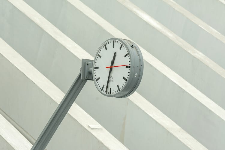 Steel Frame Clock Near The Geometric Lines On The Wall