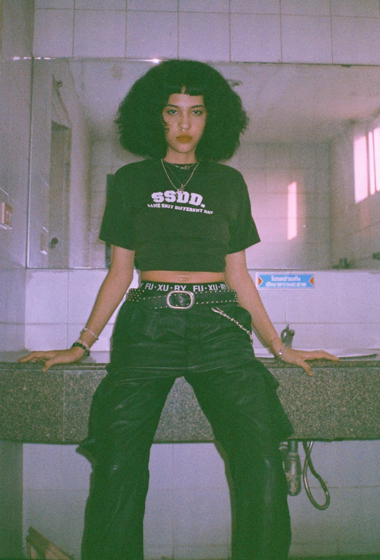 Photo Of A Woman Sitting On The Sink In A Public Restroom