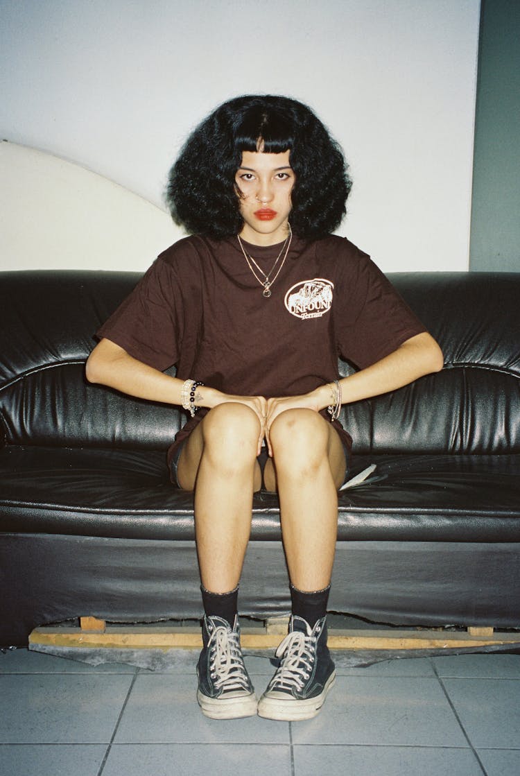 Photo Of A Young Woman Sitting On The Black Couch