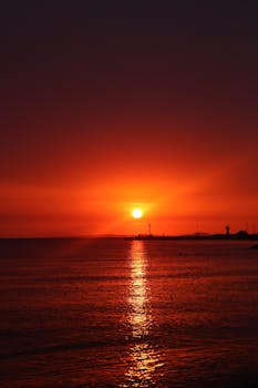 Beautiful sunset with glowing orange hues reflecting on a calm sea horizon.
