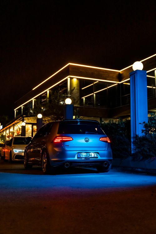 Free Illuminated car in front of building at night, showcasing modern urban vibe. Stock Photo