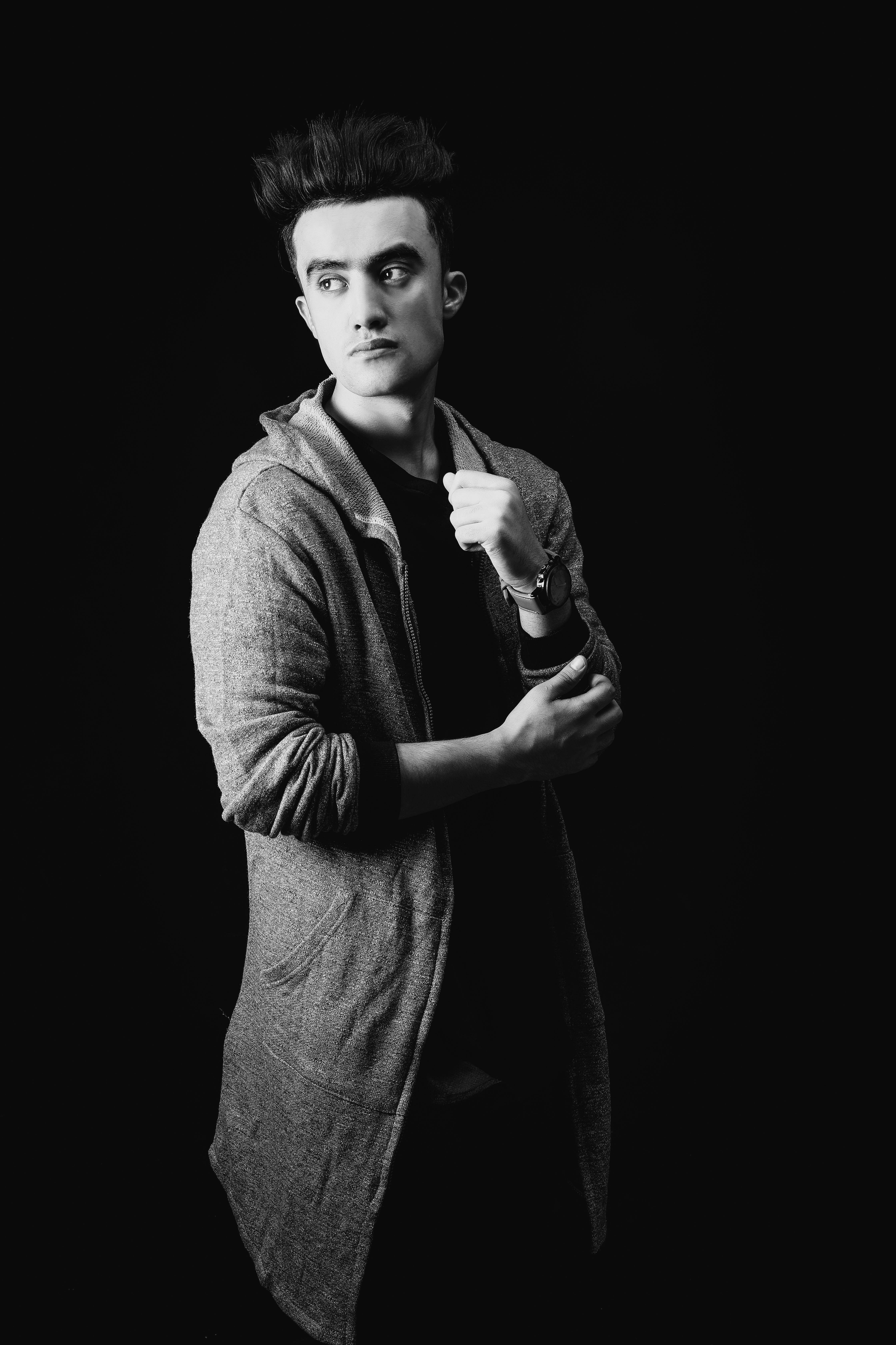 一位时尚男子身着羊毛衫，摆出严肃姿势的黑白肖像