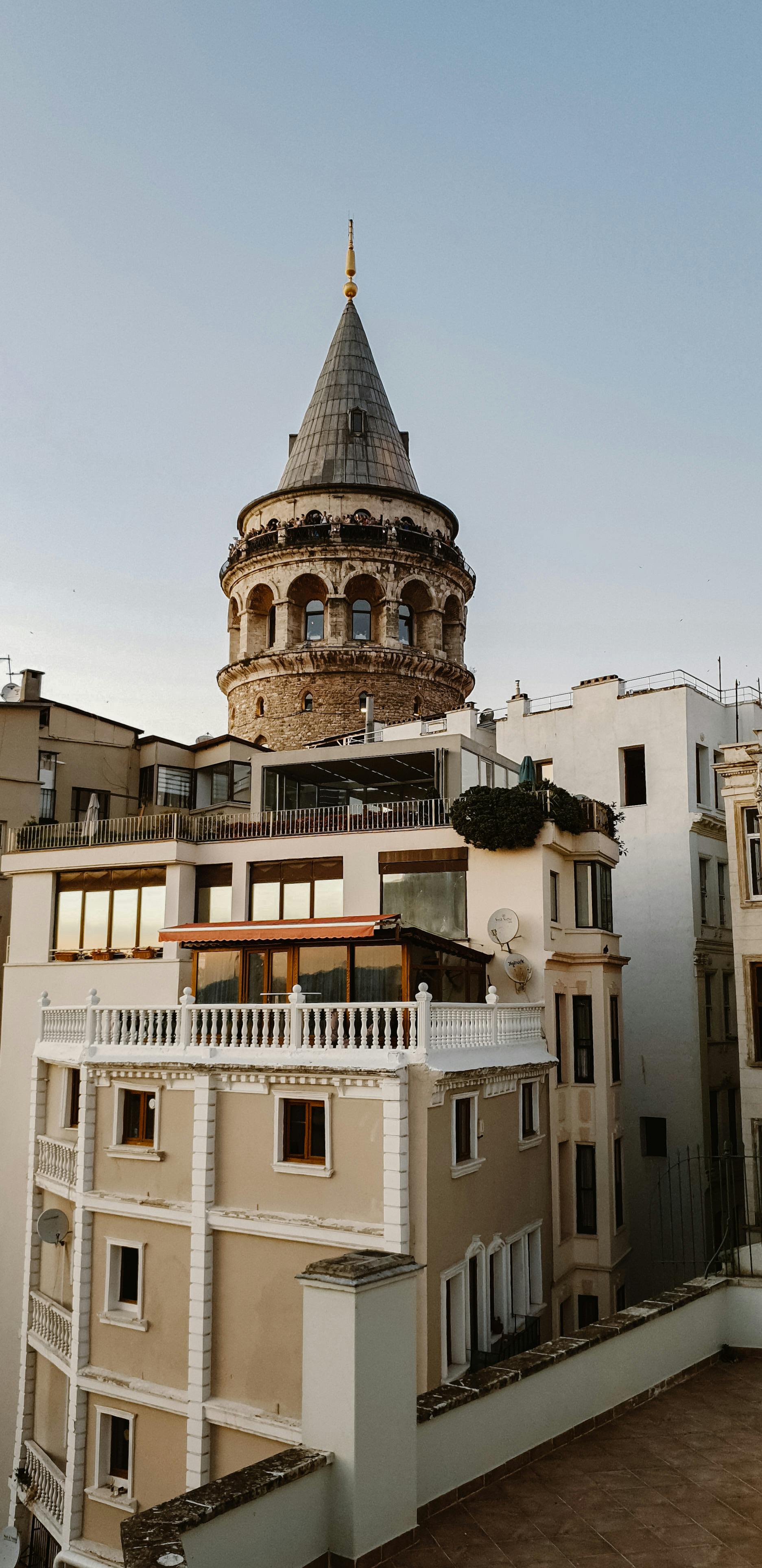 View of the historic Galata Tower amidst urban Istanbul buildings during twilight.