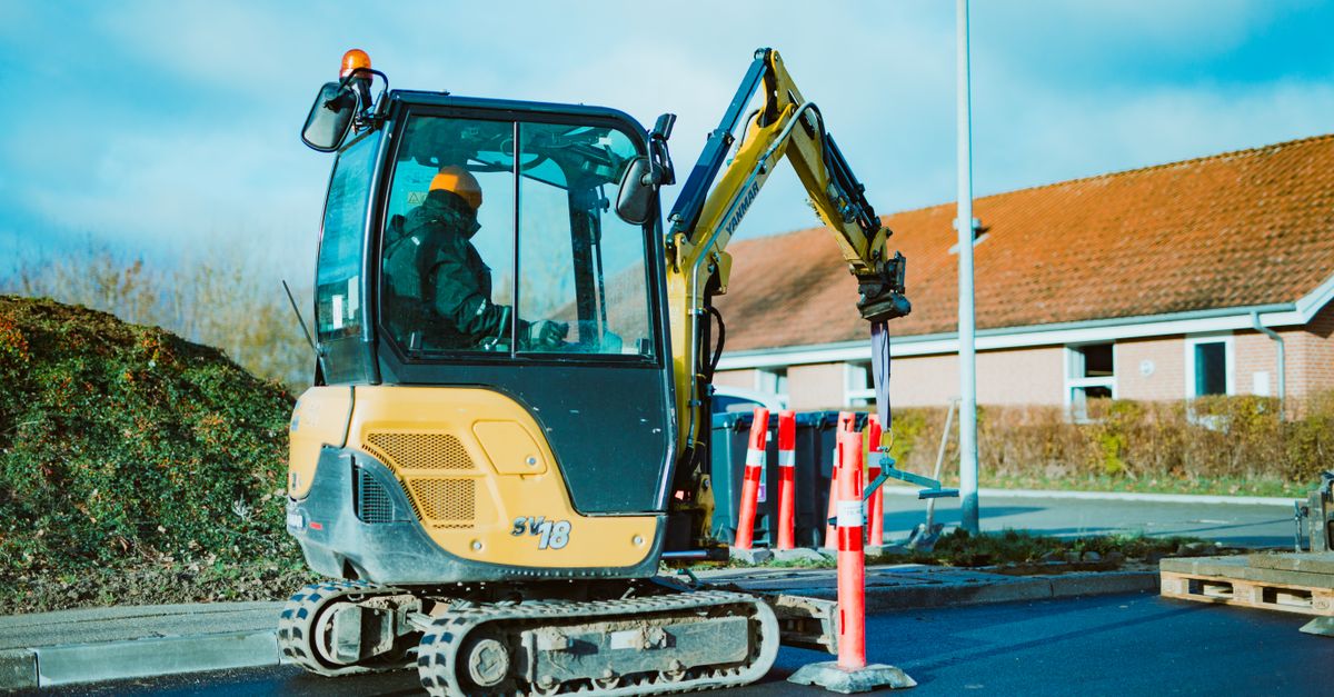 A mini excavator operating on a construction site in Odder, Denmark. A person is seen working.