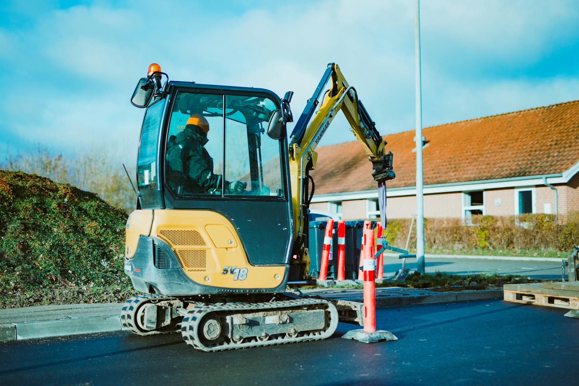 A mini excavator operating on a construction site in Odder, Denmark. A person is seen working.