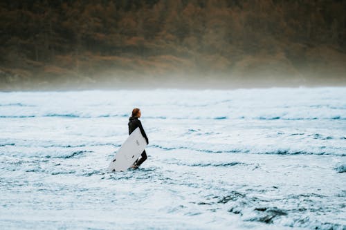 Man Walking in the Sea with a Surfboard 