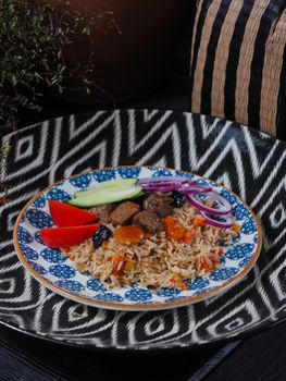 Colorful rice dish with vegetables and meat served on artistic plate.