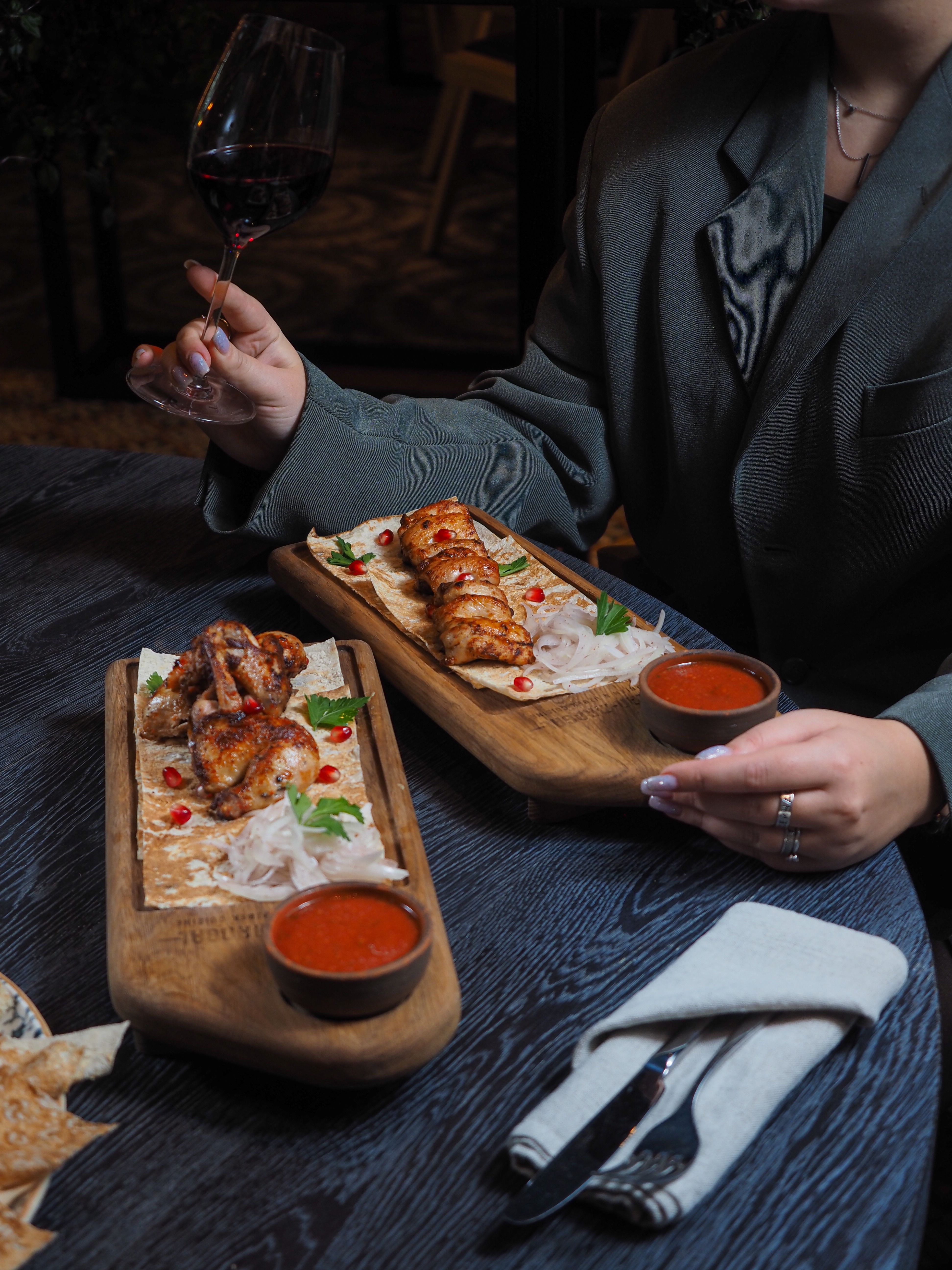 Grilled chicken wings coated in dark red scorpion harissa with glossy pomegranate glaze, garnished with fresh mint leaves and pomegranate seeds on a serving platter