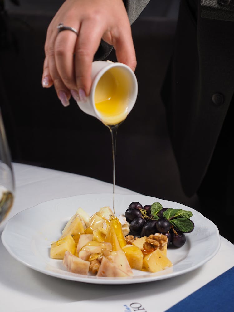 Pouring Sauce On Cheese And Grapes