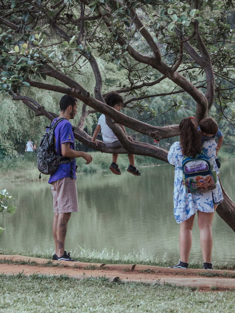 Family With Two Kids Standing By A Tree By A Pond