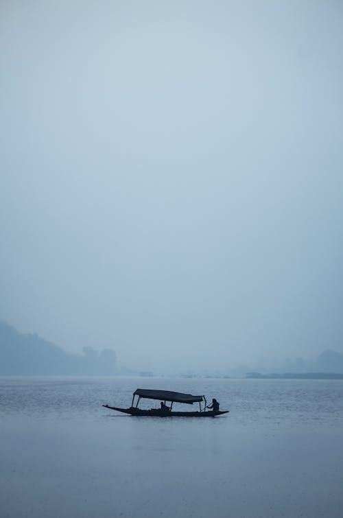 Silhouette of Fishing Boat on Misty Lake