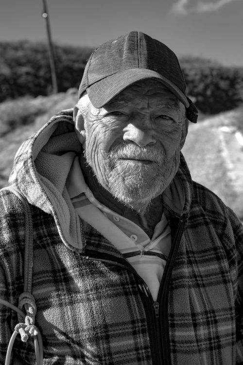 Free Black and white portrait of an elderly man in a plaid hoodie and cap outdoors. Stock Photo