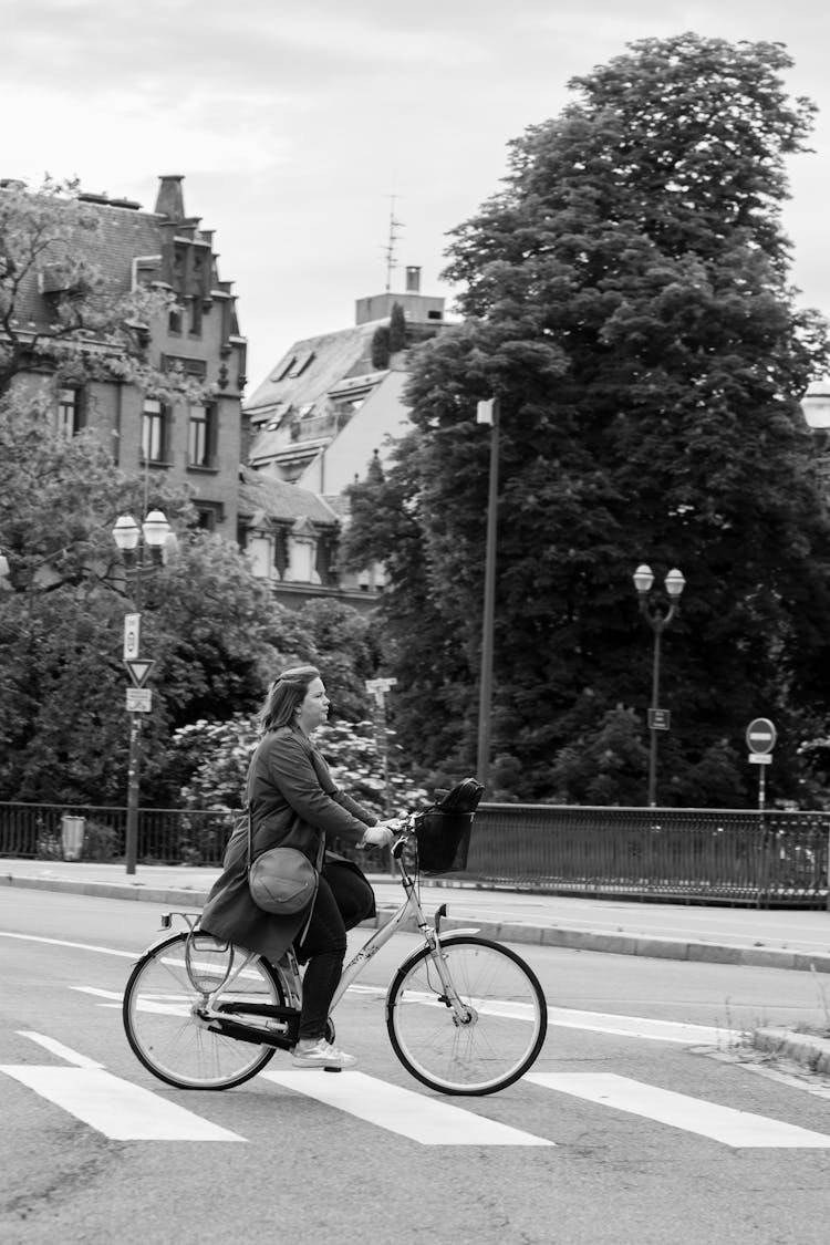 Grayscale Photo Of Woman In Black Jacket Riding On A Bicycle