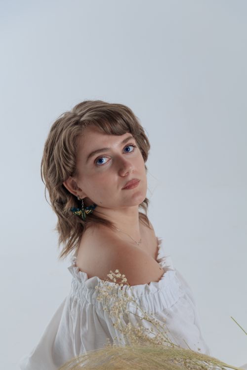 Free Elegant portrait of a woman in a white off shoulder top with gentle gaze. Stock Photo