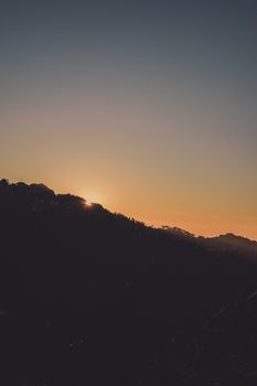 A calming view of mountains silhouetted against a vibrant sunset sky.