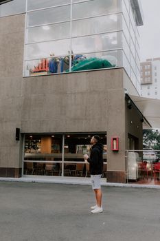 Adult man in casual attire looking up at a modern building facade in Medellín, Colombia.