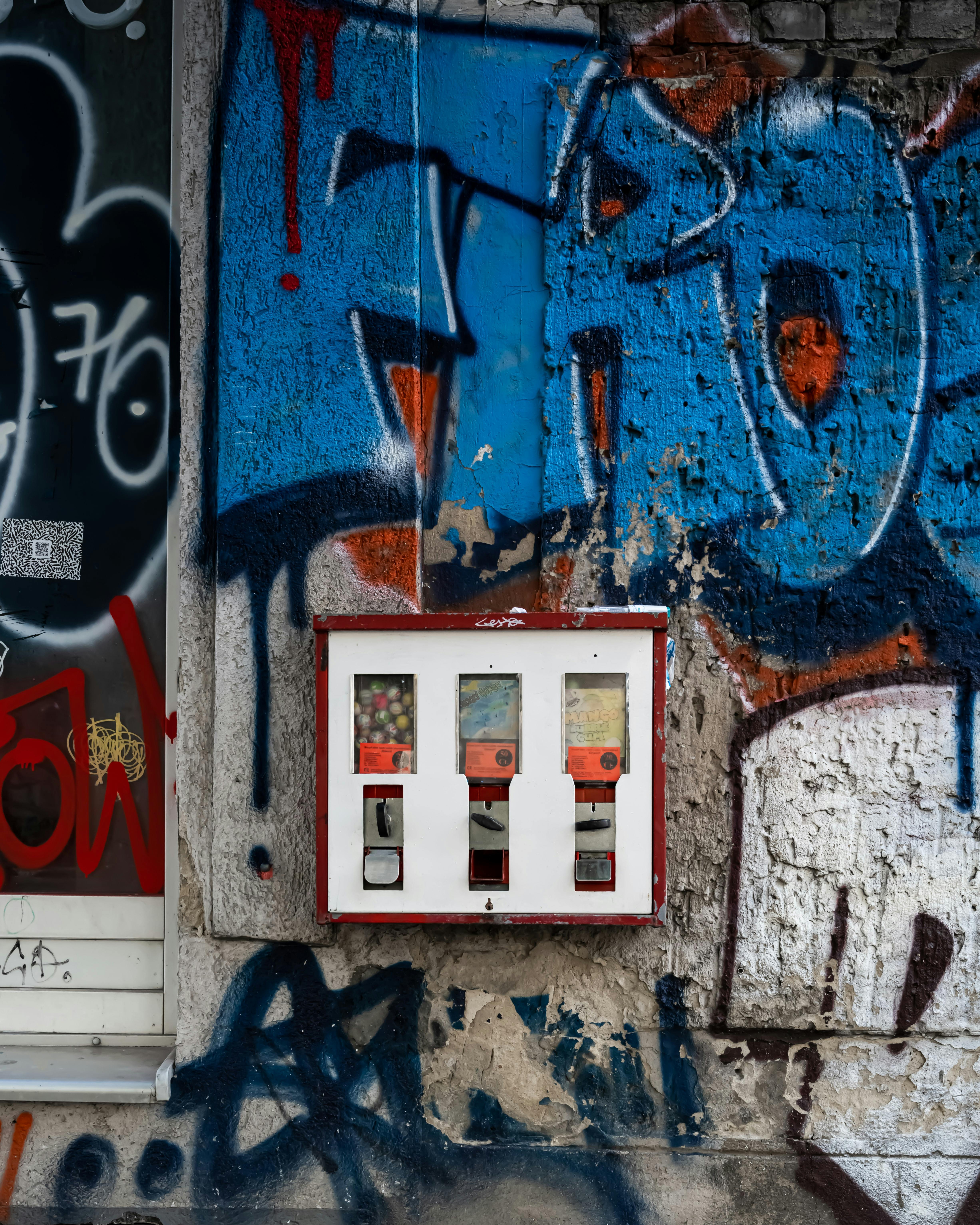 Vibrant street art graffiti with a vintage candy dispenser on a Berlin wall.