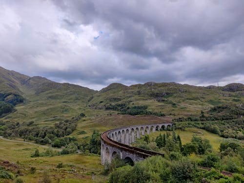 bulutlu gökyüzü, dağlık arazi, demiryolu köprüsü içeren Ücretsiz stok fotoğraf